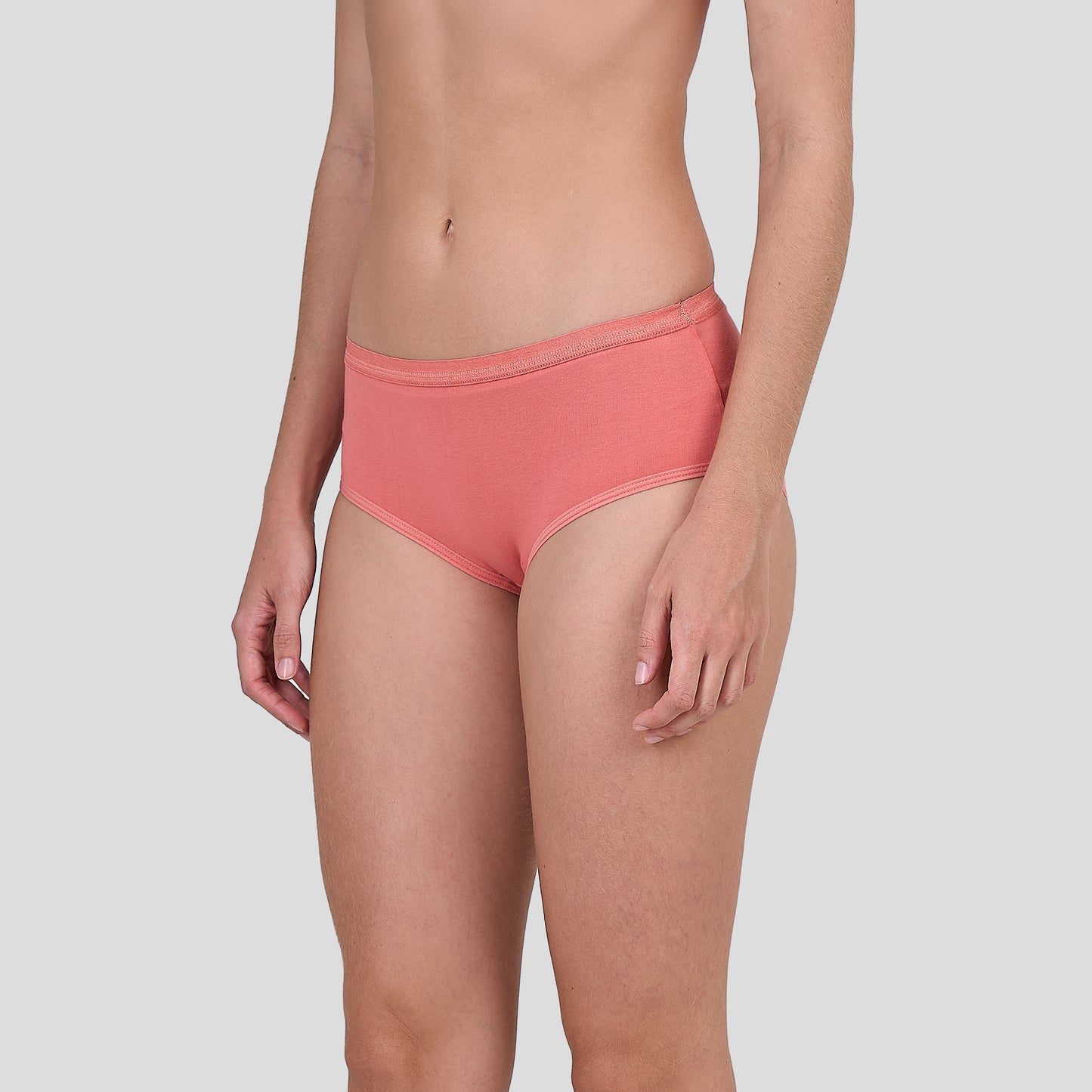 Person wearing a Dice coral pink bikini bottom on a light gray background