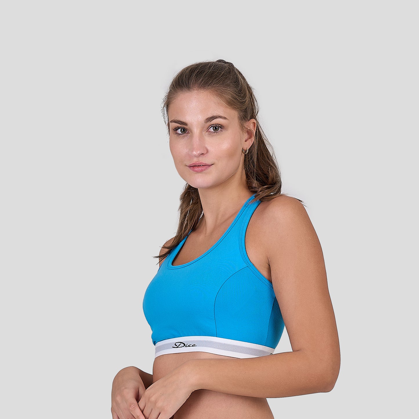 Woman wearing a Dice blue sports bra with a white brand logo on a light gray background